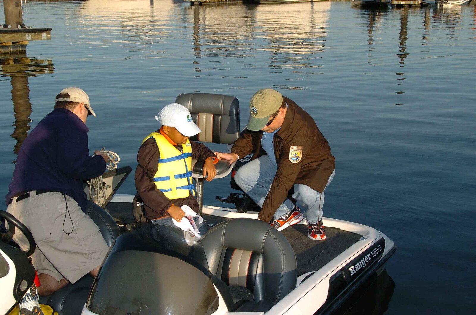 Adults supervising a child in a properly fitted life jacket aboard a boat