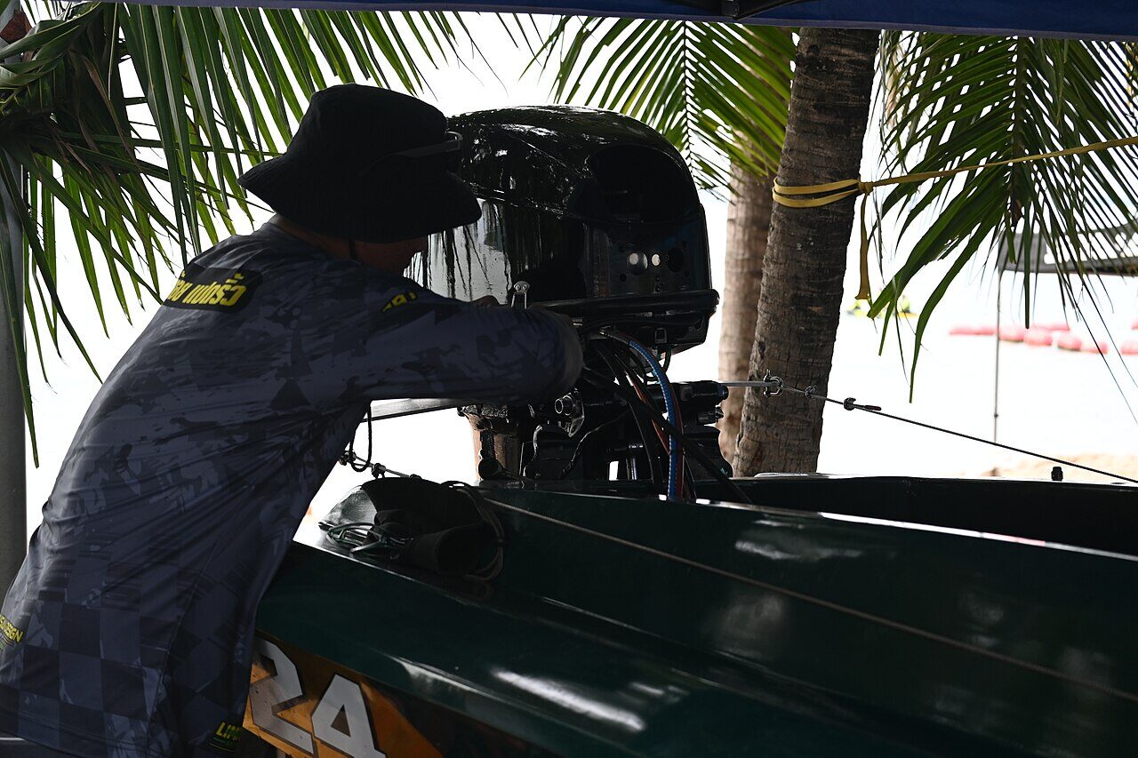 A boat owner performing careful outboard engine maintenance