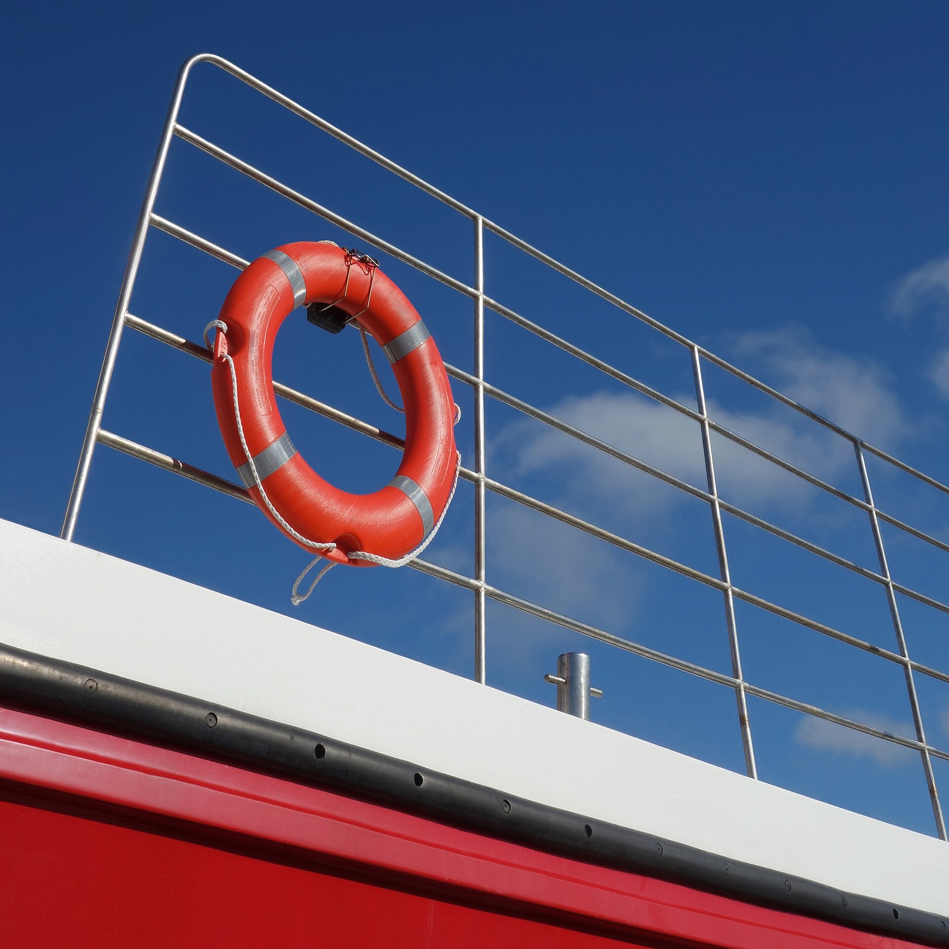 Orange ring-shaped throwable flotation device mounted on a small boat